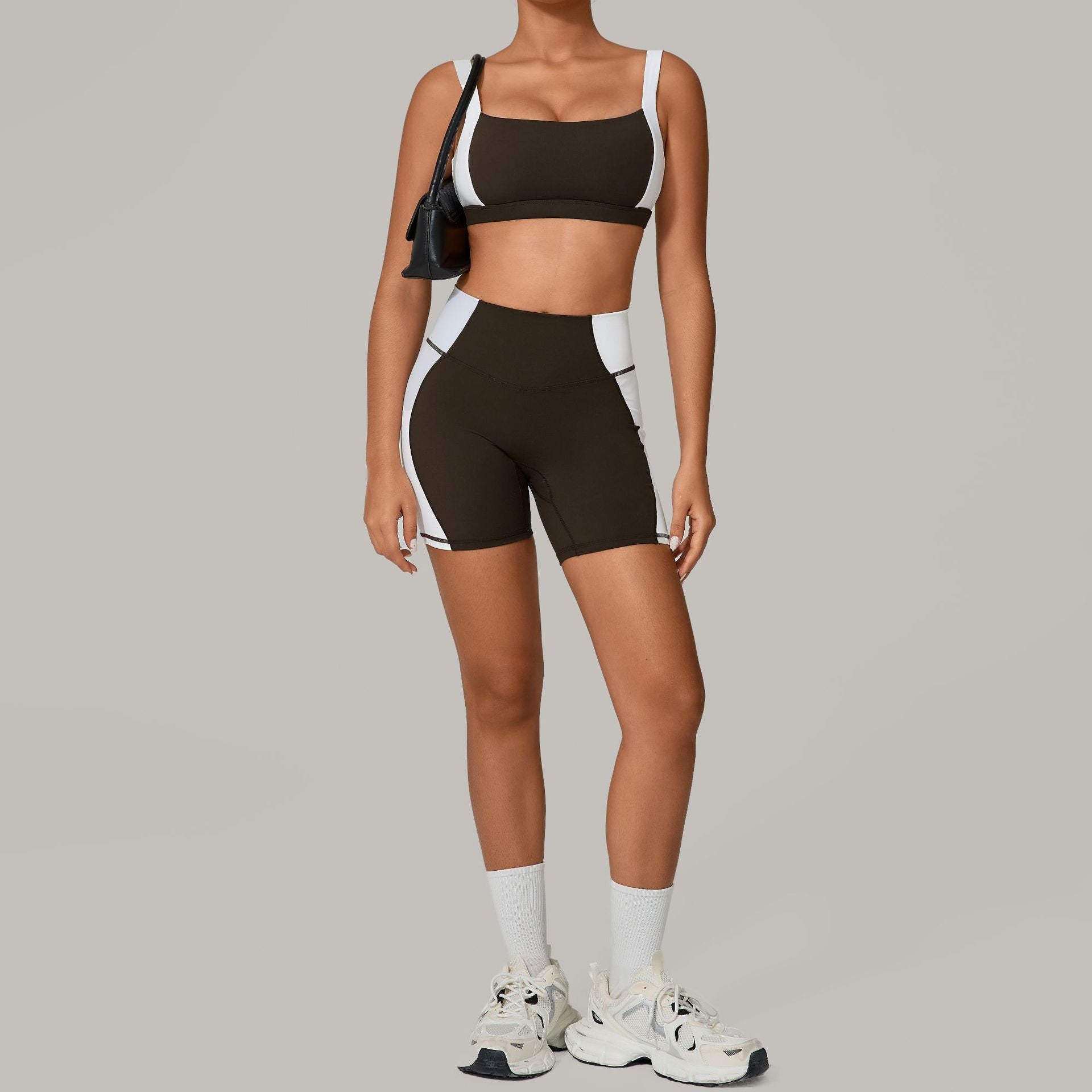 Person wearing a black sports bra and shorts with white accents on a gray background